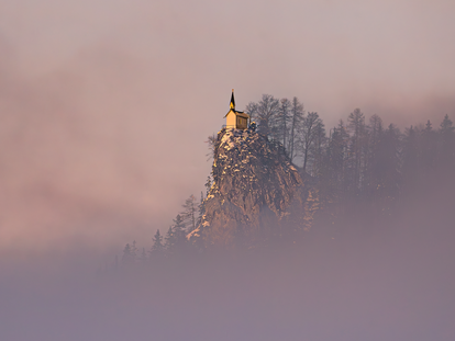 Ein Gebäude auf der Spitze eines Berges, im Hintergrund der vom Nebel verhängte Himmel