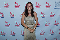 Vor einer weißen Wand mit mehreren SpaceNet Awards-Logos steht die Moderatorin Katja Holzer