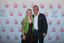Vor einer weißen Wand mit mehreren SpaceNet Awards-Logos stehen ein Mann und eine Frau