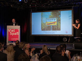 Sebastian Von Bomhard präsentiert die Gewinnerin des SpaceNet Awards vor einem Rednerpult auf der Bühne