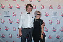 Vor einer weißen Wand mit mehreren SpaceNet Awards-Logos stehen ein Mann und eine Frau