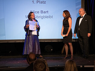 Katja Holzer und Sebastian Von Bomhard stehen gemeinsam mit der Gewinnerin des SpaceNet Awards auf der Bühne