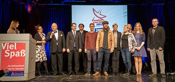 Mehrere Personen stehen auf der Bühne, im Hintergrund ist das SpaceNet Award Logo