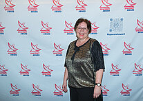 Vor einer weißen Wand mit mehreren SpaceNet Awards-Logos steht eine Frau