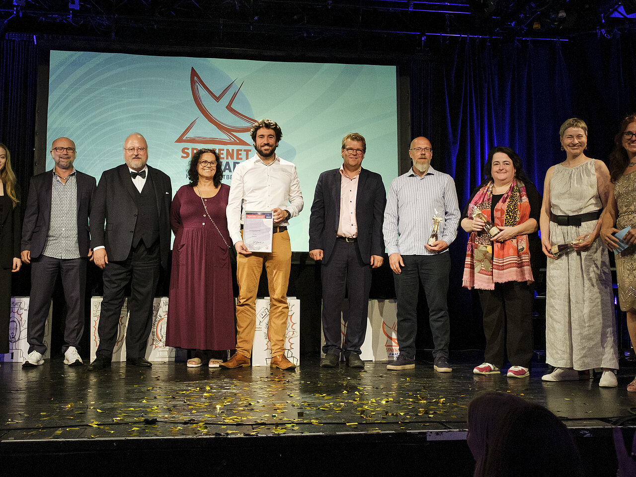 Mehrere Personen stehen auf einer Bühne, und im Hintergrund ist das SpaceNet Award Logo zu sehen