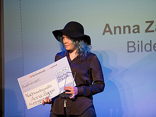 Eine Frau hält den Nachwuchspreis des SpaceNet Awards in den Händen