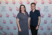 Vor einer weißen Wand mit mehreren SpaceNet Awards-Logos stehen ein Mann und eine Frau