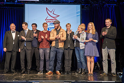 Zehn Personen klatschen auf der Bühne bei der Verleihung des SpaceNet Award 2016