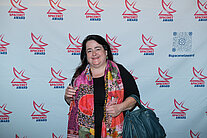 Eine Frau steht vor einer weißen Wand, die mit mehreren SpaceNet Award Logos bedeckt ist