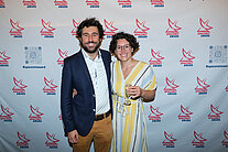 Vor einer weißen Wand mit mehreren SpaceNet Awards-Logos stehen ein Mann im Anzug und eine Frau im Kleid