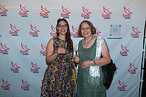 Vor einer weißen Wand mit mehreren SpaceNet Awards-Logos stehen zwei Frauen in Kleidern