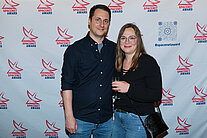 Vor einer weißen Wand mit mehreren SpaceNet Awards-Logos stehen ein Mann und eine Frau