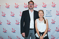 Vor einer weißen Wand mit mehreren SpaceNet Awards-Logos stehen ein Mann und eine Frau