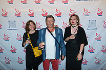 Vor einer weißen Wand mit mehreren SpaceNet Awards-Logos stehen zwei Frauen und ein Mann